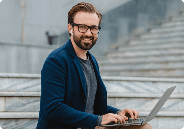 handsome-smiling-bearded-man-glasses-working-laptop